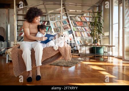 Schöne afro amerikanische Mutter liest ihre Tochter vor dem Schlafengehen Stockfoto