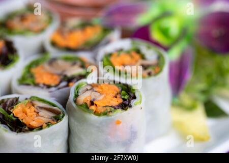 Nahaufnahme von aufgeschnittenen Sushi-Brötchen mit buntem Gemüse Im Hintergrund Stockfoto