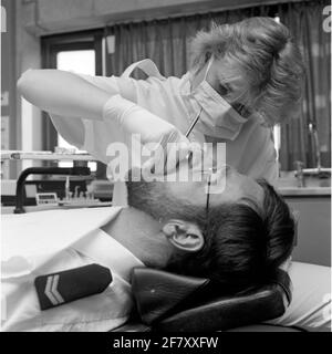 Ein Zahnarzt der Zentralkrankheit (CZB) in der Marine Barracks Willemsoord (MKWD) in Den Helder untersucht die Zähne eines Patienten (Juli 1989). Stockfoto