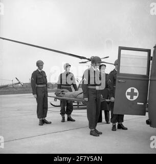 Übung Verwundeten Transport mit Bahre und Transport mit dem Krankenwagen. MGD (militärischer medizinischer Dienst). Im Hintergrund Hiller Hubschrauber, die für den Komforttransport eingesetzt werden können. Stockfoto