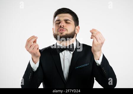 Junger Mann, der köstliche, perfekte Geste macht. Gentleman mit Bart im Smoking bewundert den Geschmack des italienischen Essens auf weißem Studiohintergrund. Bellissimo Stockfoto