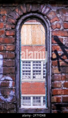 Rotes Ziegelfenster mit Blick nach draußen in einem verlassenen Gebäude Stockfoto