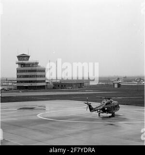 MarineLiegkamp De Kooy. Auf der linken Seite der Verkehrsturm. Im Vordergrund ein Westland Lynx SH-14B Hubschrauber, Registernummer 270. In der Mitte rechts, 2 Sikorsky S-61N Hubschrauber von KLM Noordzee Hubschraubern. Stockfoto