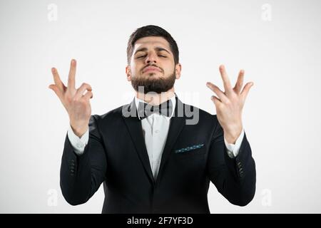 Junger Mann, der köstliche, perfekte Geste macht. Kerl mit Bart im Smoking bewundert den Geschmack der italienischen Küche auf weißem Studiohintergrund. Bellissimo Konzept. Stockfoto