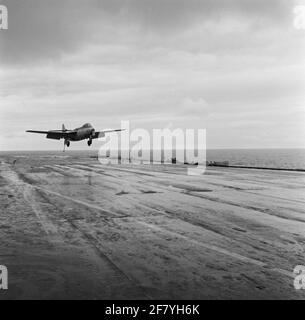 Das Hawker FGA-50 Seahawk (Jet)-Yachtflugzeug mit der Registrierung 57 (1957-1964) des Marine Aviation Service (MLD) wird am Flugzeugdeck des Flugzeuglagers HR landen Karel Doorman (R 81, ex-ehrwürdiger) im Jahr 1958. Der Bremshaken am Heck des Jägers und die Bremsseile am Flugdeck sind gut zu sehen. Stockfoto