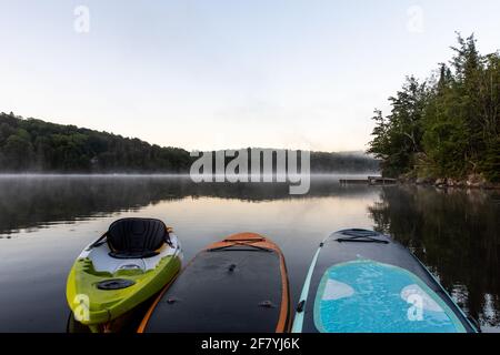 Am frühen Morgen können Sie mit dem Kajak auf einem See fahren Mit Nebel in der Ferne Stockfoto