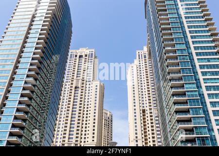 Moderne Wolkenkratzer, symmetrischer, niedriger Winkel mit blauem Himmel im Hintergrund, Dubai Marina, Vereinigte Arabische Emirate. Stockfoto