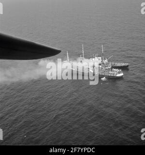 Alarmmeldung Untersuchung und Rettungsdienst. In Terschelling brennt an Bord der schwedischen Küste Sandon (Mitte). Der polnische Trawler Barycz (unten) und der niederländische Schlepper Holland (oben), Van Rederij Doeksen --terschelling, leisten Hilfe. Ein Neptun der Flugzeuggeschwader 320 ist vor Ort. Stockfoto