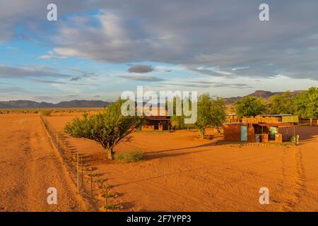 BETTA, NAMIBIA - JANUAR 05.2021: Betta Campingplatz mit den Gebäuden in der Kalahari Wüste bei Sonnenuntergang im Namib Naukluft Nationalpark, Namibia Stockfoto