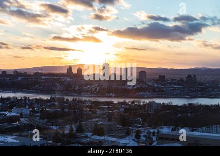 Blick auf eine Stadt auf einem Hügel mit der Sonne Licht von hinten bei Sonnenuntergang im Winter Stockfoto