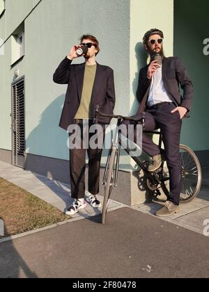 Zwei junge Freundinnen, die lässig angezogen waren, verbrachten Zeit zusammen in der Stadt und tranken beim nächsten Fahrrad Kaffee zum Mitnehmen. Stockfoto
