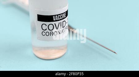 Nahaufnahme des Impfstofffläschchens COVID-19 mit Spritzennadel, Foto im Hintergrund des Krankenhauses Stockfoto