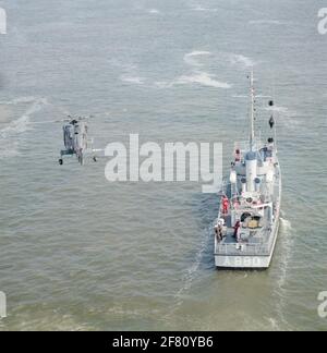 Luftaufnahme des Trainingsschiffes T.B.V. Das Royal Institute for the Marine (Kim) HR.Ms. Bulgia (A 880), die eine Person, die mit einem Hebezeug vom Hubschrauber Westland H-14 Navy Lynx mit der Registrierung 283 (1981-2012) übertragen wurde, im April 1991 durchgeführt hat. Stockfoto