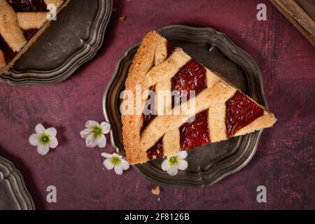 Ein Stück Kuchen namens „Linzer Torte“, ein traditionelles österreichisches Gebäck mit Obstkonserven und in Scheiben geschnittenen Nüssen im Gitterdesign Stockfoto