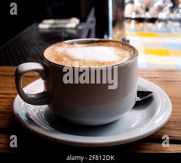 Weiße Tasse Kaffee mit Untertasse auf einem Holztisch Stockfoto