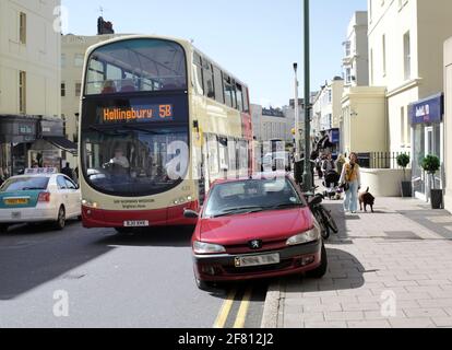 Ein illegal geparktes Auto - auf zwei gelben Linien und auf dem Bürgersteig - was zu Problemen für Busse (die den Service verlangsamen) und andere Verkehrsteilnehmer führt. Stockfoto