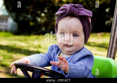 Nettes Baby Mädchen im Freien im Frühling halten Spielzeug Auto Rad Stockfoto