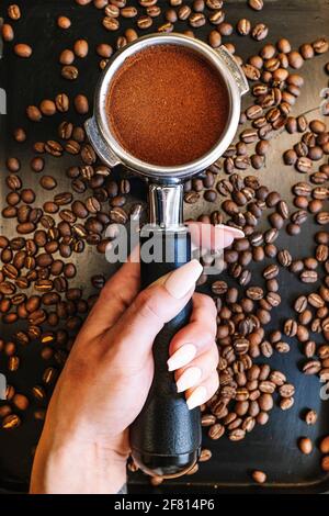 Frauenhand mit schönen Nägeln und Portafilter mit Kaffee halten Stockfoto
