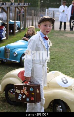 Kleiner Junge mit Koffer vor Pedalautos beim Goodwood Revival Meeting in Chichester, West Sussex UK. Stockfoto