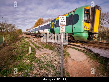 Ein Zug fährt über einen öffentlichen Fuß und überquert eine Bahnlinie in Pevensey in der Nähe von Eastbourne, East Sussex, Großbritannien. Stockfoto