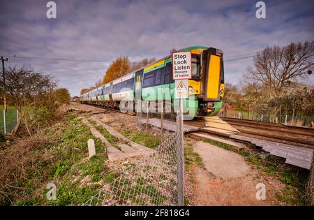 Ein Zug fährt über einen öffentlichen Fuß und überquert eine Bahnlinie in Pevensey in der Nähe von Eastbourne, East Sussex, Großbritannien. Stockfoto