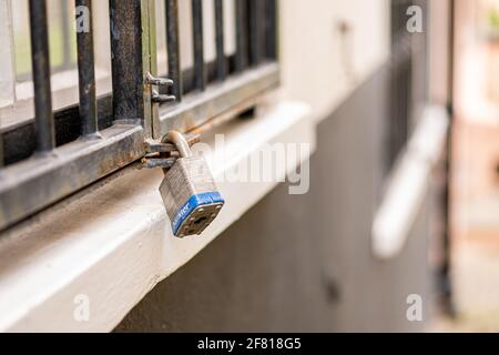 Nahaufnahme eines Vorhängeschlosses, das die Gitter über einem Fenster sichert In der Stadt Norwich Stockfoto