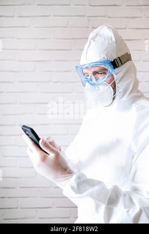Krankenschwester trägt Schutzanzug und Arbeitskleidung mit smart Telefon Stockfoto
