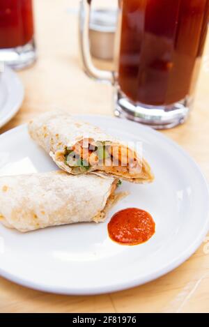 Burrito mit Clamato auf einem weißen Teller und blutiger mary In einem transparenten Glas Stockfoto