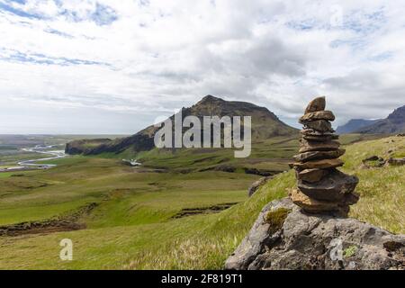 Blick auf einen Steinhaufen vor einem Berg im Hintergrund mit viel Gras auf dem Vordergrund Stockfoto