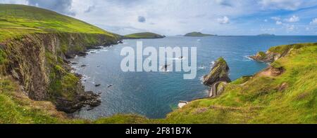 Wunderschöne Panoramaaufnahme des beeindruckenden Dunquin Pier und Hafens mit hohen Klippen, türkisfarbenem Wasser und Inseln, Dingle, Wild Atlantic Way, Kerry, Irland Stockfoto