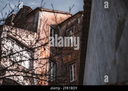 Blick von unten auf eine antike Hausfassade und Innenecke mit geschälten Wänden und mehreren Fenstern, mit einem Teilhaus im Schatten und einem weiteren p Stockfoto