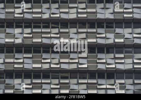 Eine graue Fassade eines modernen Bürohochhauses Mit Reihen von Fenstern und vielen kleinen Betonblöcken Jeder hat seinen eigenen zufallshori Stockfoto