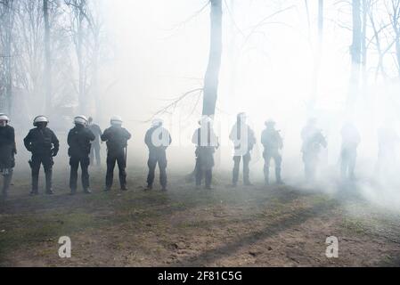 10. April 2021, Warschau, Warschau, Polen: Bei einer Anti-Regierungsdemonstration am 10. April in Warschau, Polen, werden Polizeibeamte im Rauch einer Rauchbombe gesehen, die von Demonstranten geworfen wurde. Ein paar Dutzend Menschen versammelten sich auf dem Pilsudskiego-Platz in Warschau, um gegen die Regierung und die neuesten Beschränkungen zu protestieren, die eingeführt wurden, um die Ausbreitung von SARS-CoV-2 einzudämmen. Die Demonstration wurde am selben Tag des 11. Jahrestages des Flugzeugabsturzes in Smolensk organisiert, an dem der Vorsitzende der Regierungspartei Recht und Gerechtigkeit (PiS), Jaroslaw Kaczynski, in Begleitung eines Dutzends weiterer Regierungsbehörden, teilnimmt Stockfoto