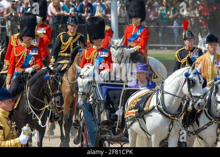Trooping the Color 17. Juni 2006. HRH die Königin fährt in einem Kutschenwagen zu ihrer Position für die Veranstaltung. S.H. Prinz Charles reitet auf dem Rücken des Pferdes (links vom Rahmen) und S.H. Prinzessin Anne reitet auf dem Rücken des Pferdes (rechts vom Rahmen). Stockfoto