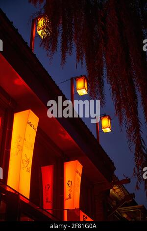 Stilvolles, beleuchtetes Lotus Blue Restaurant mit chinesischen Laternen Das Dach strahlt eine schöne warme orange-rote Farbe gegen die Tiefblau Stockfoto