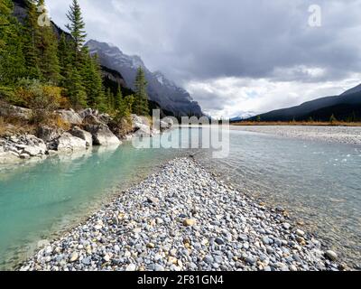 Türkisfarbener Wasserfluss an einem bewölkten Tag in den rockies Mit Felsen im Vordergrund Stockfoto