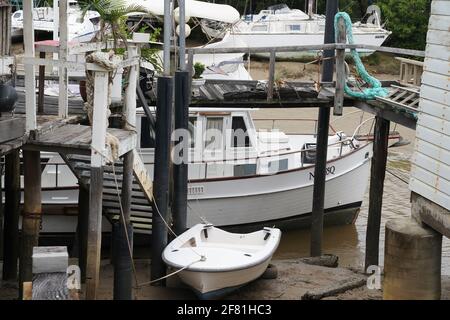 Yeppoon, Queensland, Australien - 2021. April: Boote liegen an einem alten Holzsteg in einem Küstenbach Stockfoto