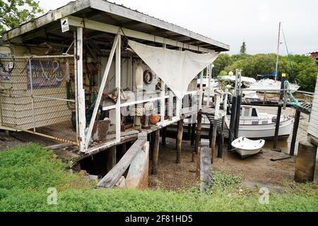 Yeppoon, Queensland, Australien - 2021. April: Bei Ebbe vertäuten Boote zwischen heruntergekommenen Hütten an einem alten Holzsteg im Küstenbach Stockfoto