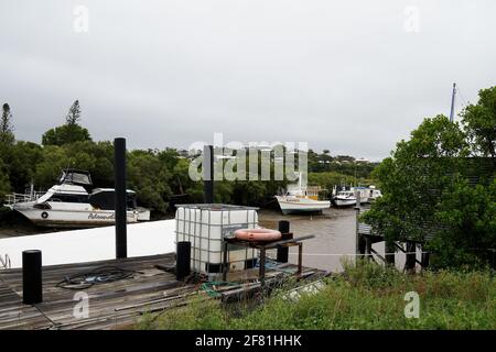 Yeppoon, Queensland, Australien - 2021. April: Alte Holzbrücke am Bachufer mit Booten im Hintergrund Stockfoto