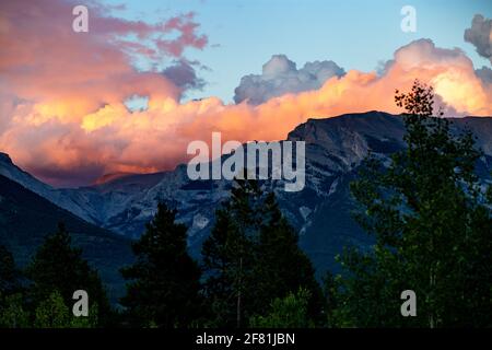 Im Sommer rosafarbene Wolken über hohen Bergen mit dunklem Gipfel Stockfoto