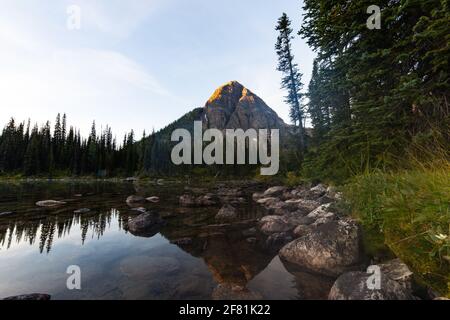 Hoher Gipfel hinter einem See mit einfallenden Sonnenstrahlen Die Spitze des Berges Stockfoto