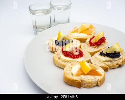 Eine Nahaufnahme von verschiedenen Fischrogen Vorspeisen und Gläser Wodka auf weißem Hintergrund Stockfoto