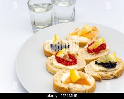 Eine Nahaufnahme von verschiedenen Fischrogen Vorspeisen und Gläser Wodka auf weißem Hintergrund Stockfoto