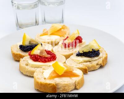 Eine Nahaufnahme von verschiedenen Fischrogen Vorspeisen und Gläser Wodka auf weißem Hintergrund Stockfoto