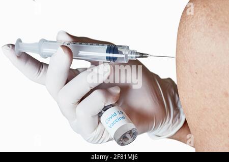 Mit Handschuhen behandelte Hand, die eine Injektion in den Arm verabreicht und dabei gehalten wird Die Flasche mit Impfstoffen, die auf Weiß isoliert ist Stockfoto