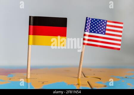 Die kleinen Flaggen von Deutschland und den USA auf einem Holzstab auf dem Globus befestigt Stockfoto