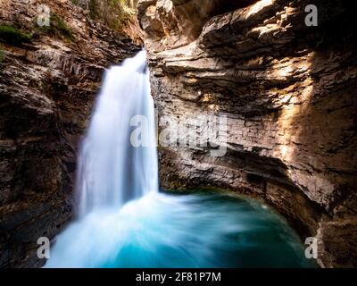 Weißer Wasserfall in einer Höhle mit Felswänden im Sommer Mit Licht Stockfoto