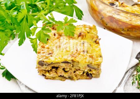 Auflauf aus Hackfleisch, Zwiebeln und Auberginen, übergossen mit einer Sauce aus Eiern, Milch, Käse und Mehl auf einem Teller auf einem Handtuch vor dem Hintergrund des Lichts Stockfoto