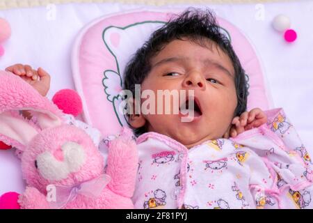 Ein Monat alte niedliche Baby Mädchen Gähnen in ihrer ersten Foto-Session feiert 1 Monat Geburtstag. Zeit für ein verträumtes Nickerchen. Stockfoto