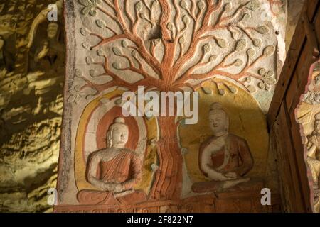 Bodhi-Baum und zwei Buddha-sitzende Statuen in den Yungang-Grotten, frühe buddhistische Höhlentempel, UNESCO-Weltkulturerbe, Shanxi, China. Stockfoto